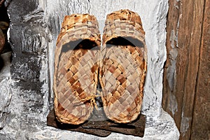 Old bast shoes are dried on a stone stove in an old village hut