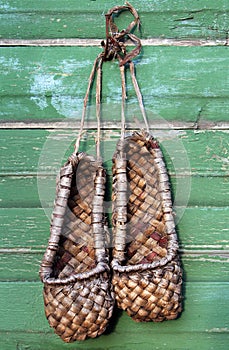 Old bast shoes traditional russian footwear on a green wall