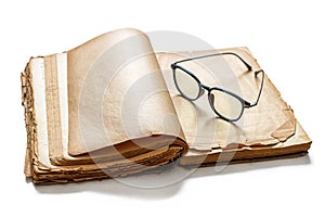An old, battered book with yellowed pages and reading glasses