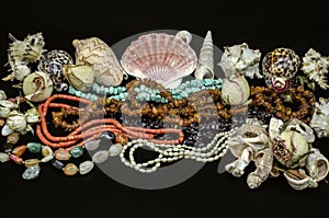 Old beads of turquoise, red coral, amber, garnet stone, multi-colored agate, pearls among various shells on black background