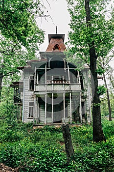 Old beautiful abandoned wooden house among trees and green grass