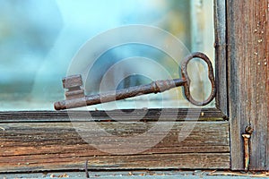 An old beautiful rusty key is lying on the window of an old house