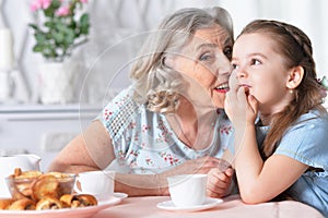 Close up portrait of old woman with a young girl drinking tea