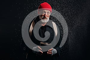 Old beggar man in street clothes stand under rain