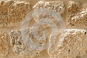 Old beige stone wall background texture close up. Castle wall surface, antique natural stonewall