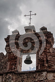 Old bell on ruin with a cross