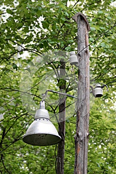 An old bell-shaped street lamp and two old-fashioned ceramic insulators mounted on an old wooden pole