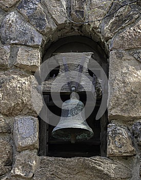 Old bell in stone wall arch