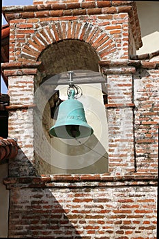 An old bell tower with a weathered green bell at the Mission San Antonio de Padua, Jolon CA.