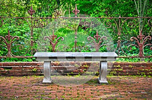 Old bench in formal English garden with ornate wrought iron fence