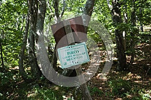 Old metal plate on wooden pole in forest with inscription Parco Naturale Regionale dell`Aveto means Aveto Regional Natural Park photo