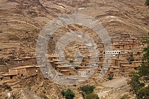 Old berber village oasis with houses build of clay bricks in front of impressive high rugged red mountain face