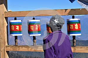 Old Bhutanese lady and Old wooden Tibetan prayer wheels at Chele la pass , Bhutan