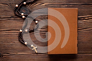 Old Bible book with wooden christian rosary beads