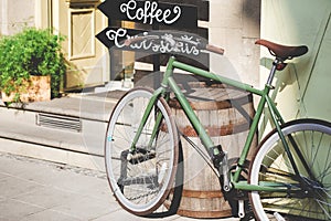 Old bicycle against coffeehouse on sunny day