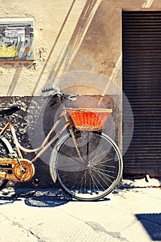 Old bicycle with a basket against the wall advertisement in Italy