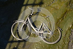 Old bicycle on the bottom of dried river or channel in the dirt silt in Europe. Concept of pollution, ecology and