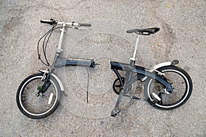 Old bicycle with a frame broken in half lying on an asphalt