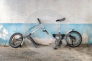 Old bicycle with a frame broken in half stands against the wall