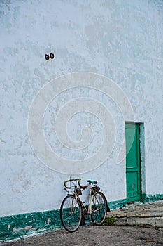 An old bicycle leaning against a dilapidated blue wall.