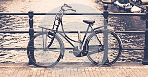 Old bicycle locked on a bridge over water canal, Amsterdam, Netherlands