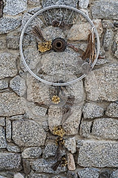 Old bicycle wheel and dry flowers presented as decoration on a stones wall in France.