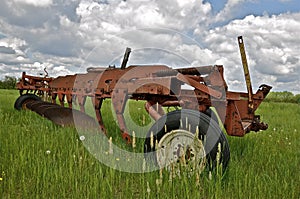 Old big plow parked in the grass