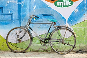 Old bike against the colored wall with milk written on.