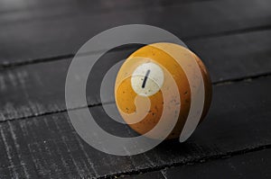 Old billiard ball number 1 orange color on black wooden table background, copy space