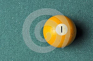 Old billiard ball number 1 yellow color on green billiard table, copy space