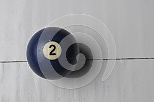 Old billiard ball number 2 blue color on white wooden table background, copy space