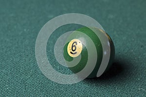 Old billiard ball number 6 green color on green billiard table, copy space