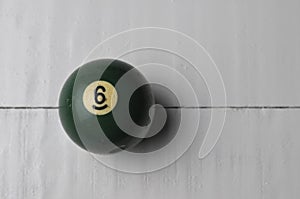 Old billiard ball number 6 green color on white wooden table background, copy space