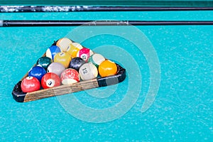 old billiard balls in wooden rack on green table