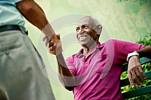 Old black and caucasian men meeting and shaking hands in park