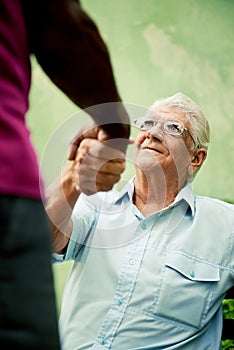 Old black and caucasian men meeting and shaking hands in park