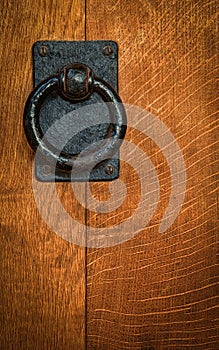 Old black circular knocker on oak door