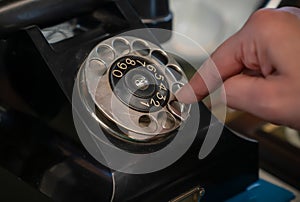 Old black color rotary telephone with woman fingers