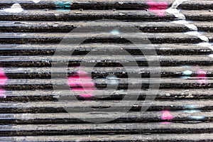 Old black with colorful spots empty metal roller shutter door background texture. Copy space