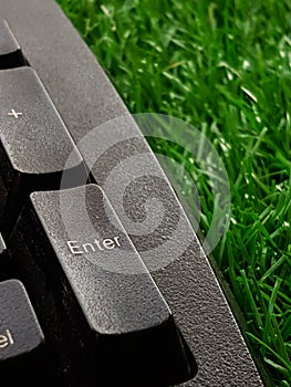 Old black computer keyboard on decorate green artificial grass