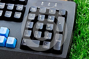 Old black computer keyboard on decorate green artificial grass