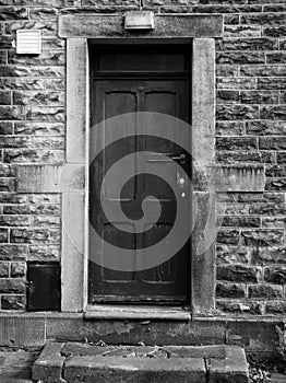 Old black door with faded and flaking paintwork photo