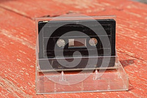 Old black film audio cassette on a wooden table