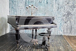 Old black grand piano stands in room with ragged