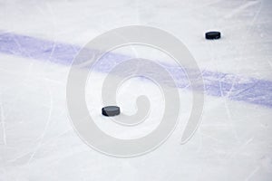 Old , black ice hockey puck near blue line in ice hockey rink