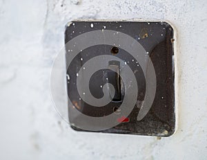 Old black light switch on a white wall