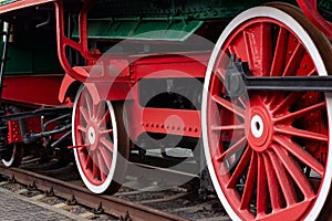 Old black and red retro steam locomotive wheels at the railway station. Vintage train staying on the railroad.