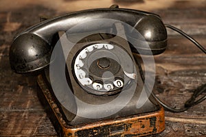 Old black retro phone on a wooden table, rotary phone