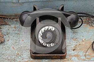 Old black retro phone on a wooden table, rotary phone