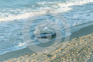 Old black rubber tire left on beach, environment pollution concept, selective focus, color toned picture. Discarded old tyre in bl